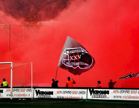Bandierone sventolato in curva tra i fumogeni rossi